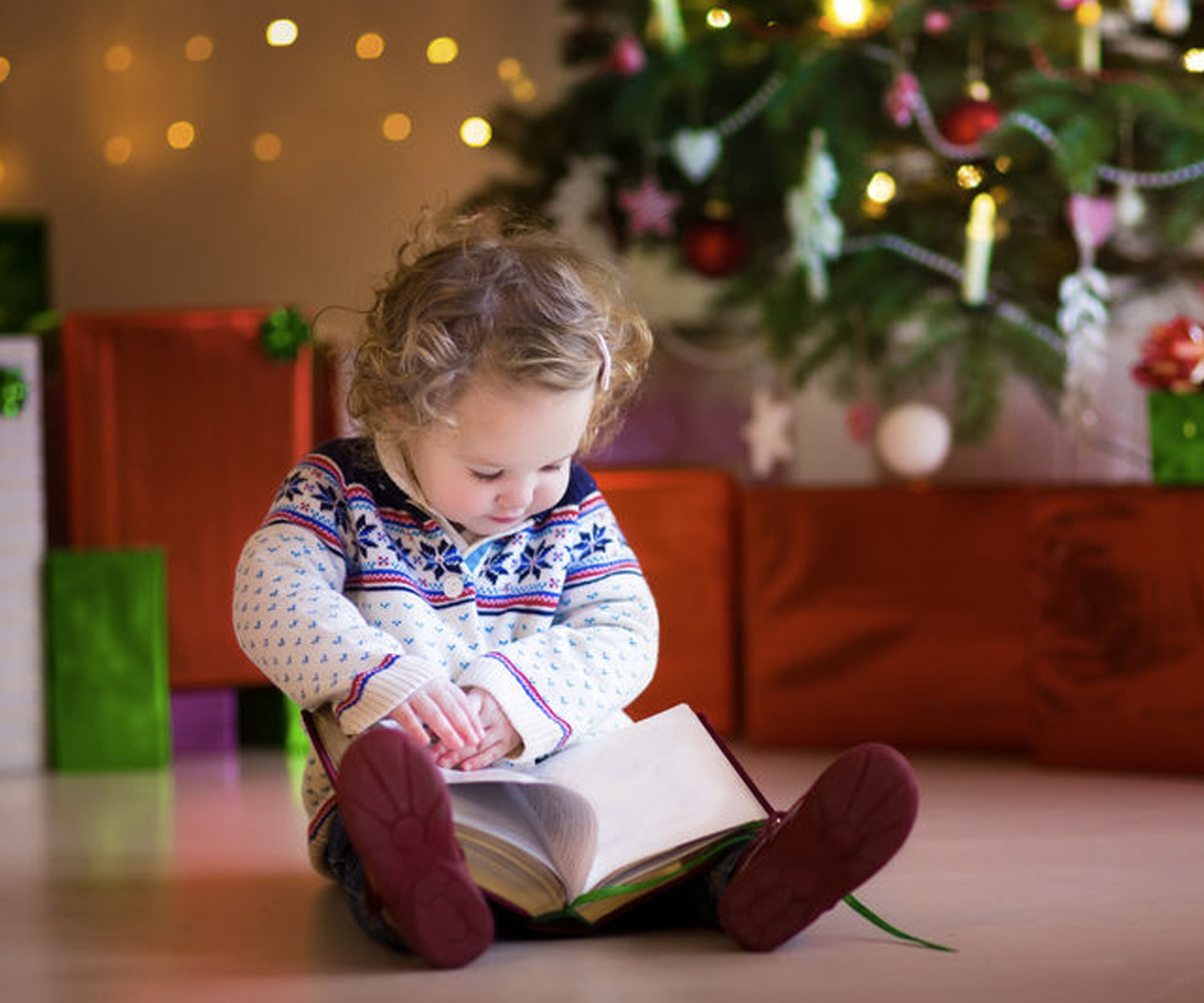 Title: Girl reading a book by a Christmas Tree